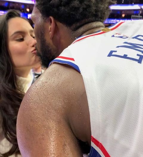 Joel Embiid and Anne de Paula kissing during a game 